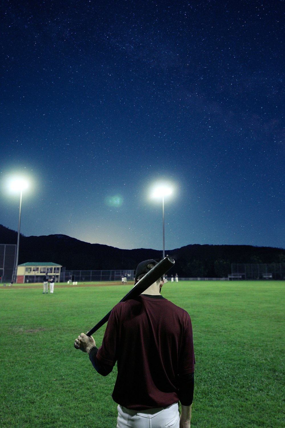 man holding baseball bat on green field