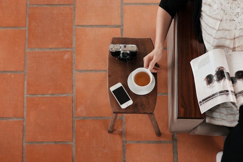 person sitting on sofa while reading brochure holding teacup