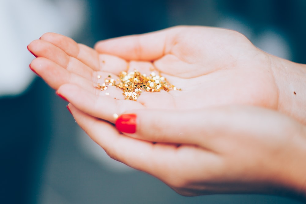 person holding gold-colored beads