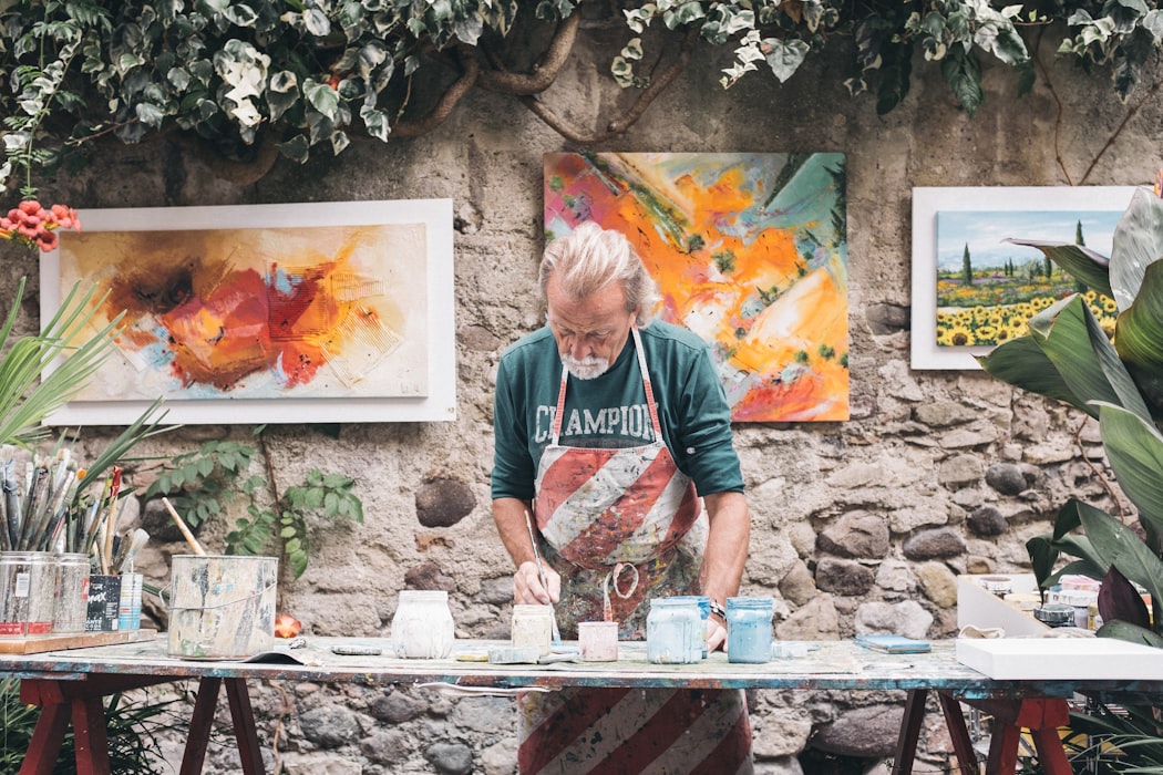 Man in striped apron paints canvases in Bardolino