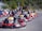 A group of happy people racing go-karts on an outdoor track during a sunny day.
