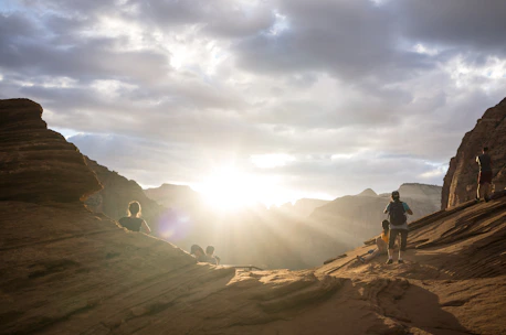 A group of hikers pausing at a scenic overlook with red rock formations under a bright blue sky.