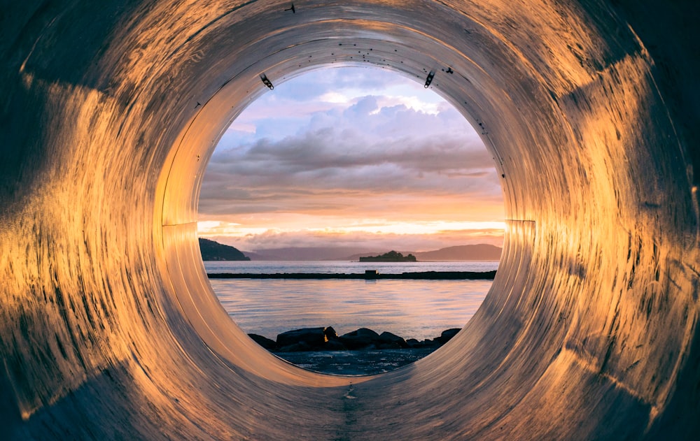 Sunset over the sea seen from the inside of a large pipe