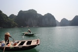 Boat gliding through emerald waters surrounded by towering limestone karsts in Tam Coc.