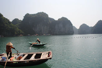 A traditional Vietnamese boat floating on the calm waters of Ha Long Bay surrounded by limestone karsts.