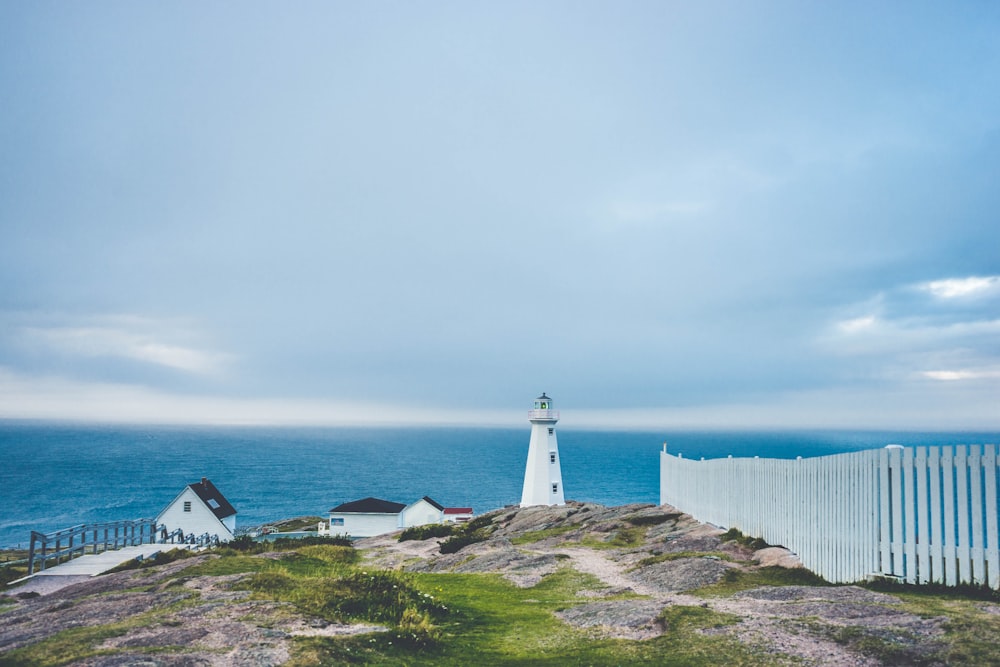 lighthouse on cliff near fence and house