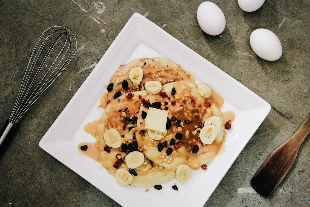 plate of pancake topped with sliced bananas and chocolate syrup