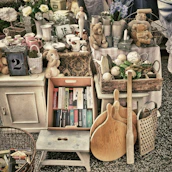 A quiet corner of a flea market in Paris, with antique furniture and collectibles bathed in gentle afternoon light.