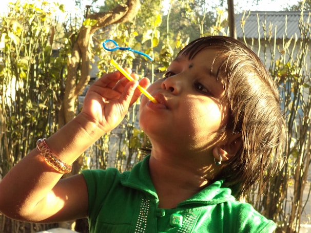 A joyful moment of a child playing with slime outdoors, sunlight highlighting the slime’s shine.