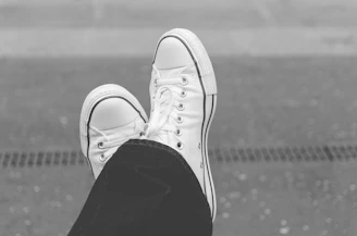 Monochrome image of relaxed-fit pants styled with urban sneakers on cobblestone streets.