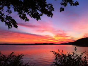 A vibrant photo of a sunset over a quiet lake, reflecting warm colors and peaceful surroundings.