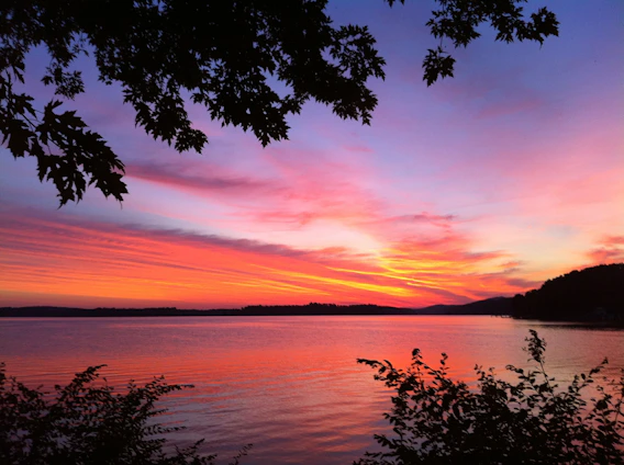 A vibrant photo of a sunset over a quiet lake, reflecting warm colors and peaceful surroundings.