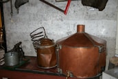 Artisan distiller inspecting copper stills under warm, vintage lighting with subtle shadows.