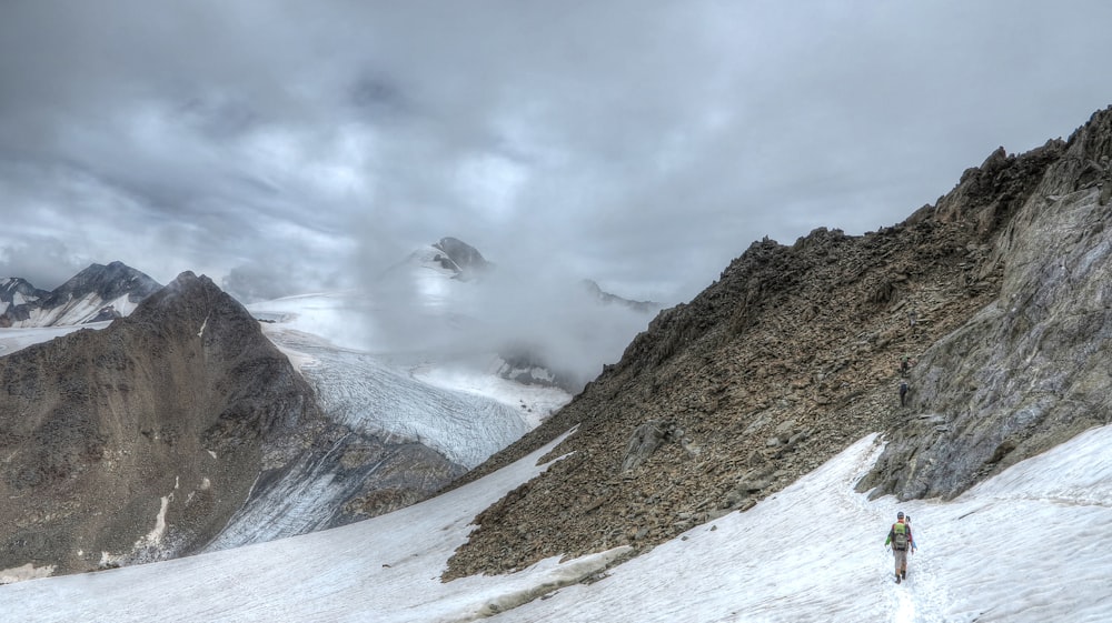 person walking on snow covered mountain during daytime