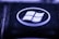 A close-up view of a key on a keyboard featuring a recognizable Windows logo. The key is predominantly black with the logo in white, encircled within a glossy surface. The lighting creates a moody, bluish-purple hue over the key, highlighting its textured surface.