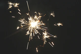 A dynamic close-up of a high-precision cold spark machine emitting bright sparks against a dark stage background.