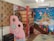 A colorful, whimsical room filled with vibrant decorations. There is a play structure resembling a gingerbread house, adorned with candy-themed designs, including lollipops and gumdrops. The walls are decorated with cheerful murals featuring stars, clouds, teddy bears, and a castle, all in bright, playful colors. The overall atmosphere is child-friendly, with a fantasy theme.