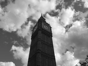 Black and white photograph of a vintage clock tower silhouetted against a cloudy sky.