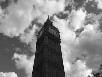 Black and white photograph of a vintage clock tower silhouetted against a cloudy sky.