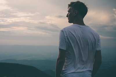 man standing facing mountains during sunset thoughtful zoom background