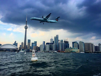 An airplane flying over the Statue of Liberty with Mumbai’s Gateway of India in the background.