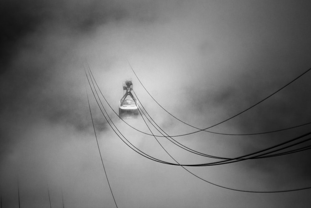 Foto in scala di grigi della funivia in mezzo alle nuvole