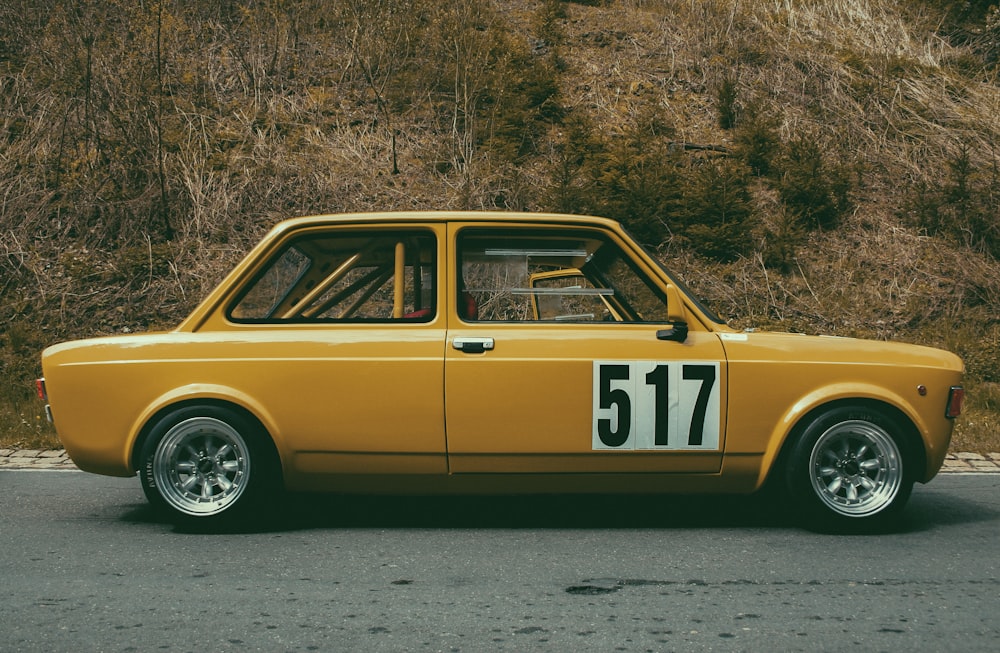 classic yellow and white sedan parked beside green plant