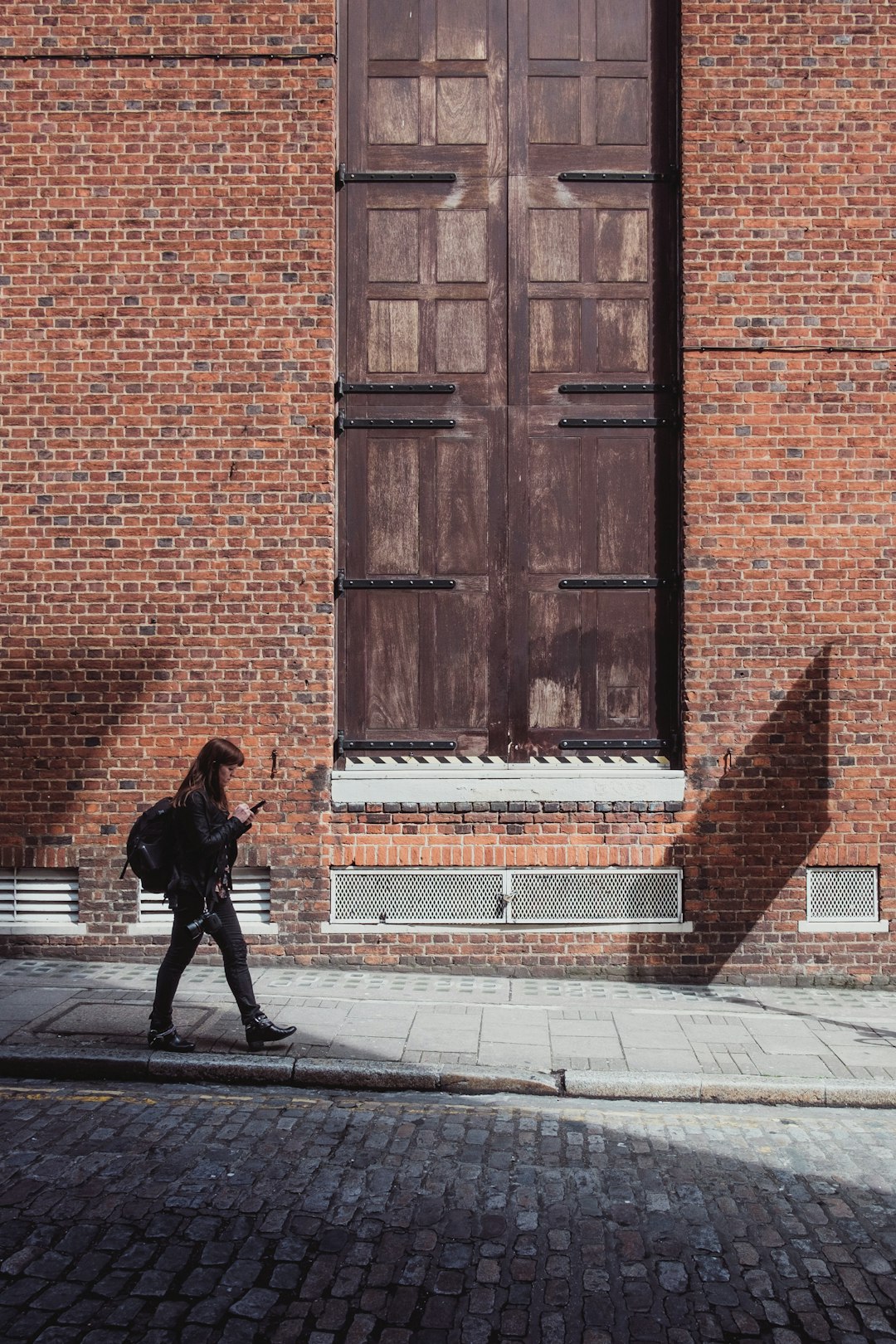 woman walking near brown wooden door during daytime