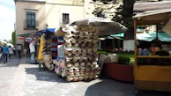 A model wearing a light beige brimora bucket hat walking along a bustling street market.