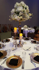 A beautifully set black and gold luxury event table with elegant floral centerpieces.