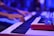 Close-up of hands playing a keyboard with colorful sound equipment in the background.