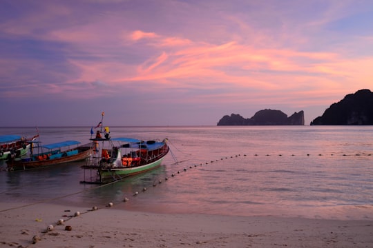 green boat on beach during sunset in Phi Phi Islands Thailand