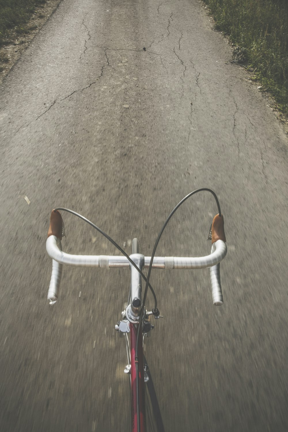 Bicicleta de carretera gris y roja entre hierba