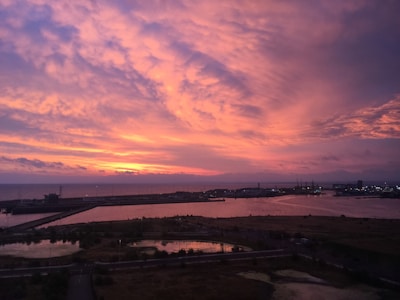 A vibrant sunset over a busy harbor filled with vessels.