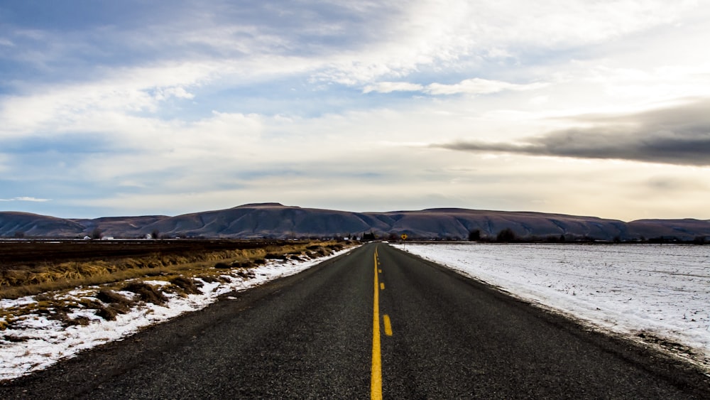 snow beside road under blue sky during day time