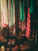 A closet filled with a variety of clothing items and shoes. The clothes are organized on hangers, displaying different patterns such as polka dots and stripes in colors like green, pink, and black. The bottom part shows an assortment of shoes arranged in pairs, with various designs including striped, open-toed, and heeled footwear.