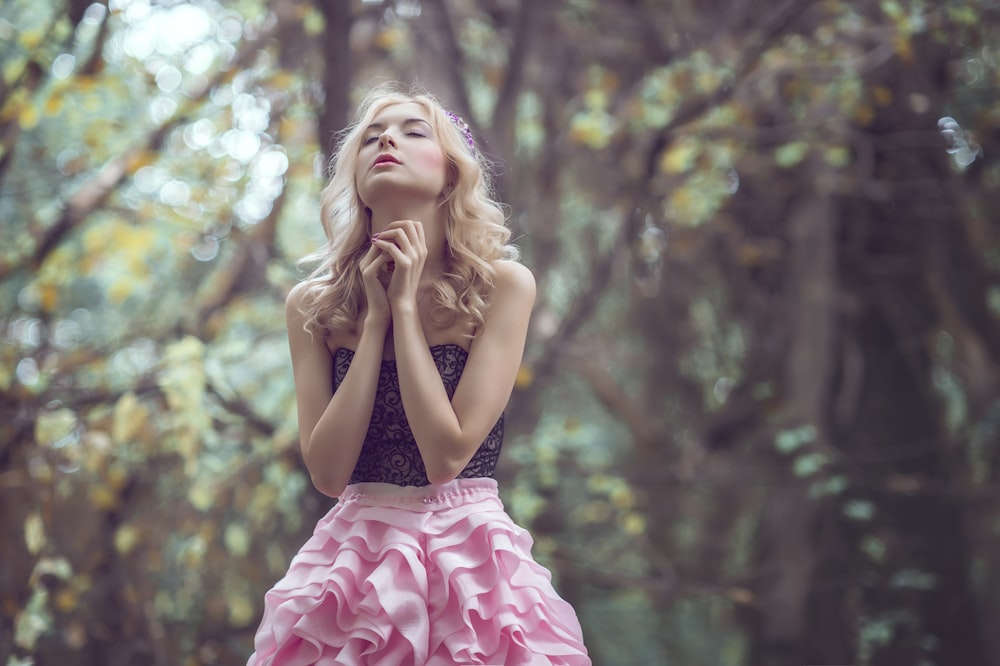 woman standing in the middle of the forest holding hands together during daytime