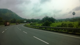A fleet of trucks transporting vehicles on a highway surrounded by lush greenery.