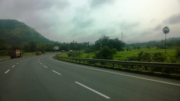 A convoy of trucks traveling on a Brazilian highway surrounded by green landscapes.