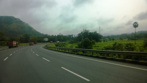 A fleet of trucks transporting vehicles on a highway surrounded by lush greenery.