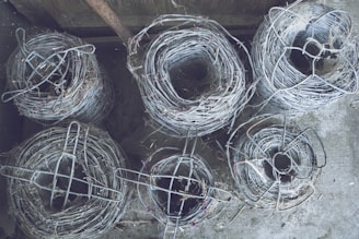Photo of galvanized and PVC wire mesh rolls stacked in a factory setting.