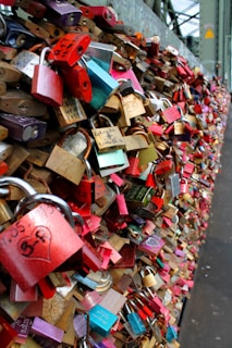 A dense collection of colorful padlocks attached to a metal fence or railing, often seen as symbols of love and commitment.