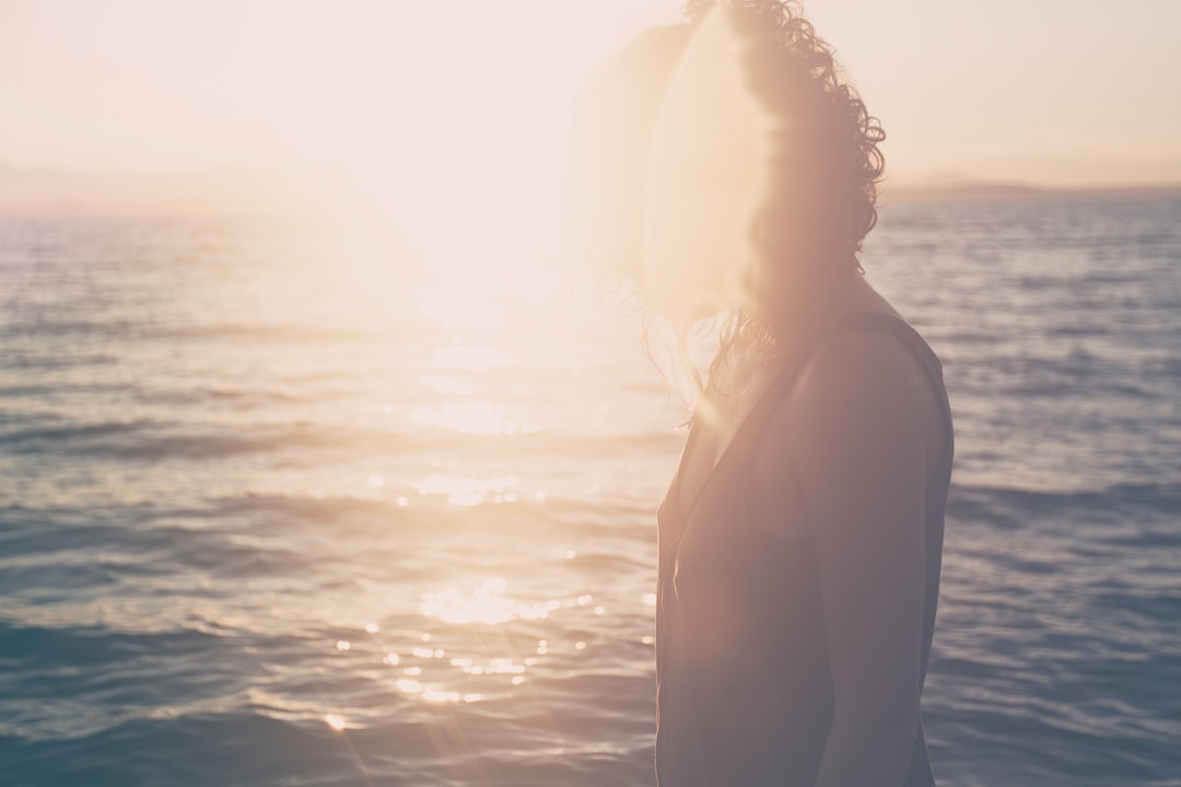 woman standing on body of water under sunset