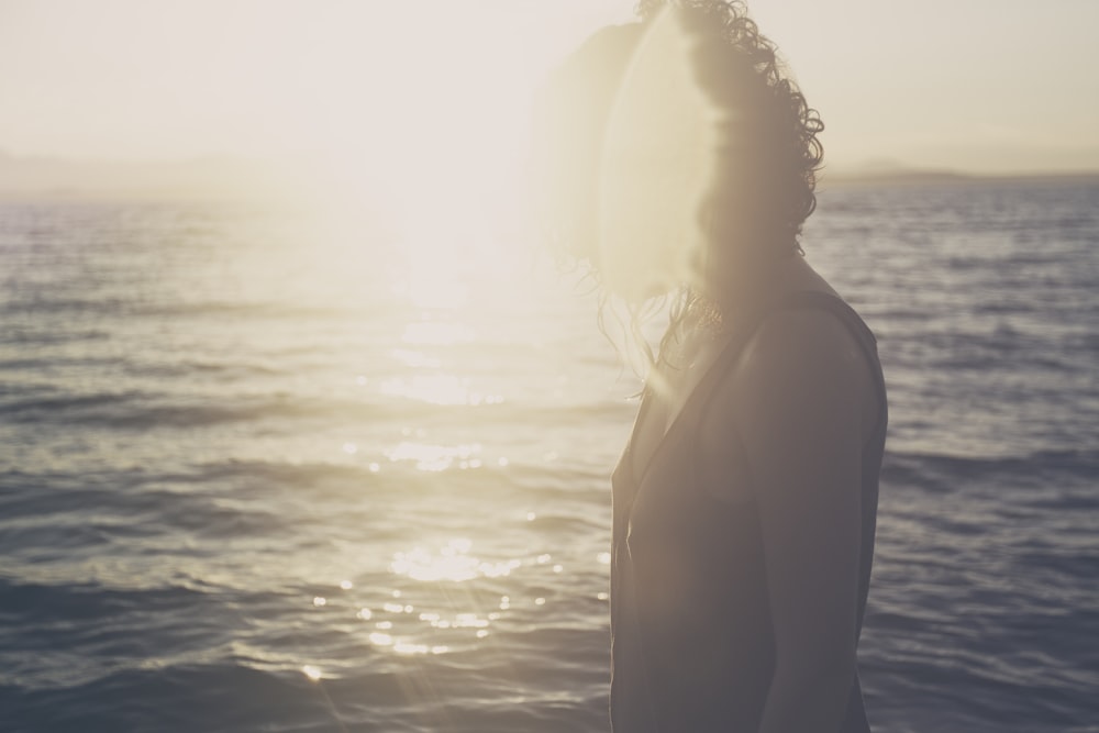 donna in piedi sullo specchio d'acqua sotto il tramonto