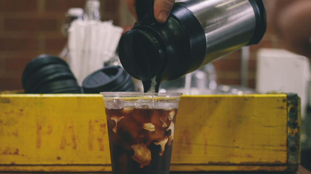 a person pouring a drink into a cup