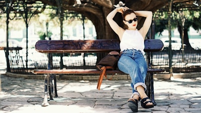 An outdoor scene showing a tote bag and sunglasses resting on a park bench.