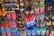 A colorful array of various flip-flops and sandals hanging on display. They feature multiple designs and patterns, including floral prints, stripes, and logos in a vibrant mix of colors like red, blue, green, and pink.