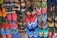 A colorful array of various flip-flops and sandals hanging on display. They feature multiple designs and patterns, including floral prints, stripes, and logos in a vibrant mix of colors like red, blue, green, and pink.