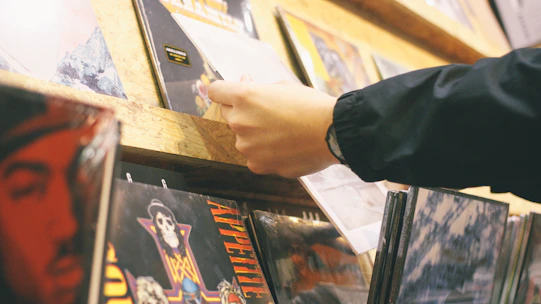 Close-up of a hand browsing through a collection of classic rock CDs