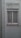 A closed white-framed window with vertical blinds is set into a light gray wall. The wall shows signs of aging and weathering, with some peeling paint above the window. Several thin lines or wires are attached to the window sill, stretching outward, possibly for drying clothes.